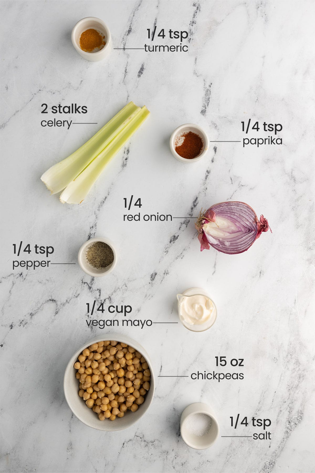 overhead view of all ingredients for vegan egg salad - turmeric, paprika, celery, red onion, pepper, vegan mayo, chickpeas, salt