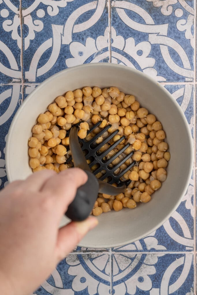 Smashing chickpeas with a potato masher