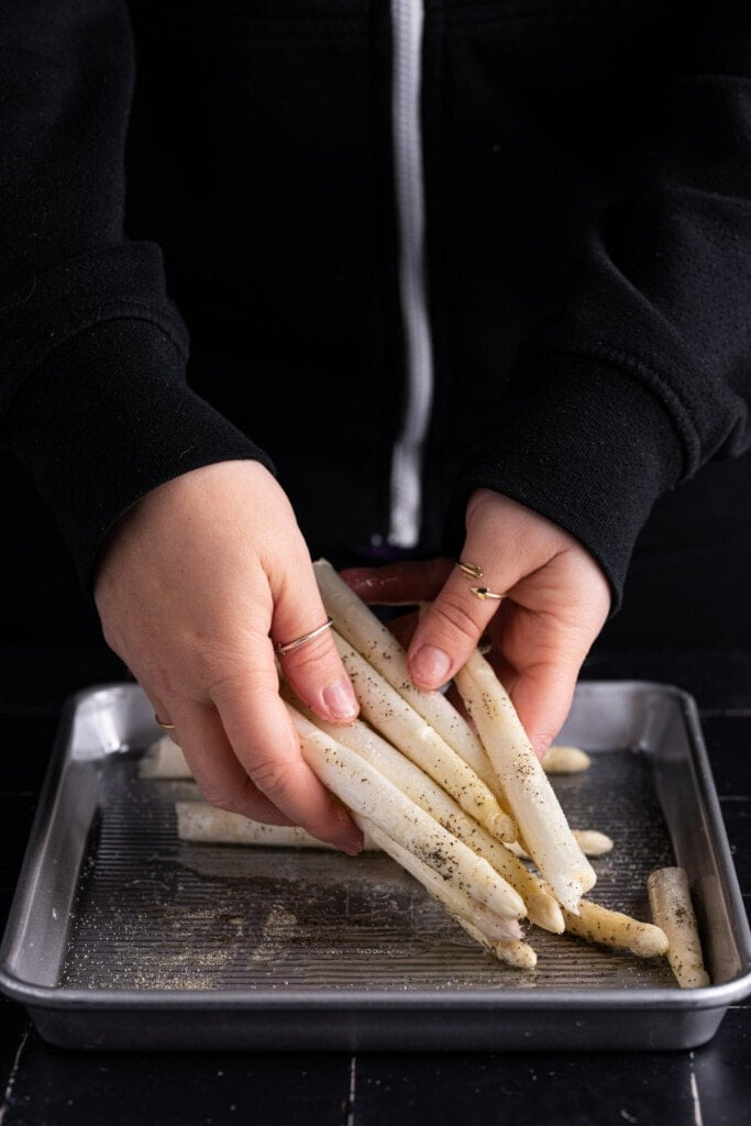 Tossing white asparagus in salt pepper and olive oil