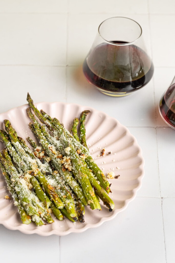 Cropped image of Garlic Parmesan Asparagus with two glasses of wine