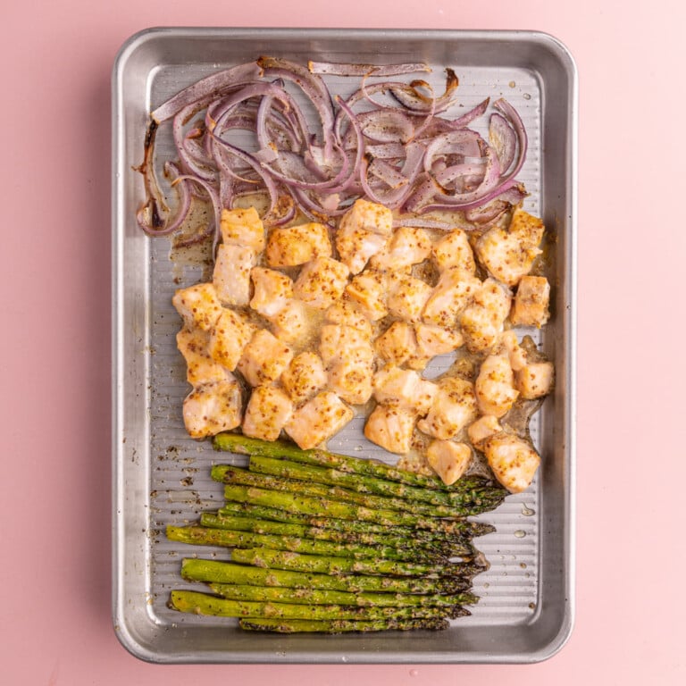 Roasted red onion, salmon, and asparagus on a baking sheet