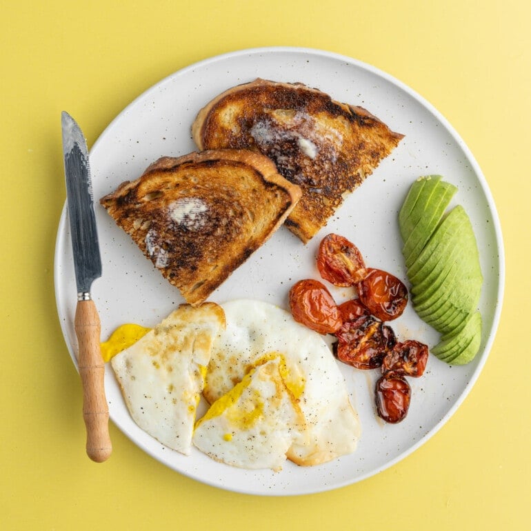 Over Hard Eggs served with toast and avocado and roasted tomatoes