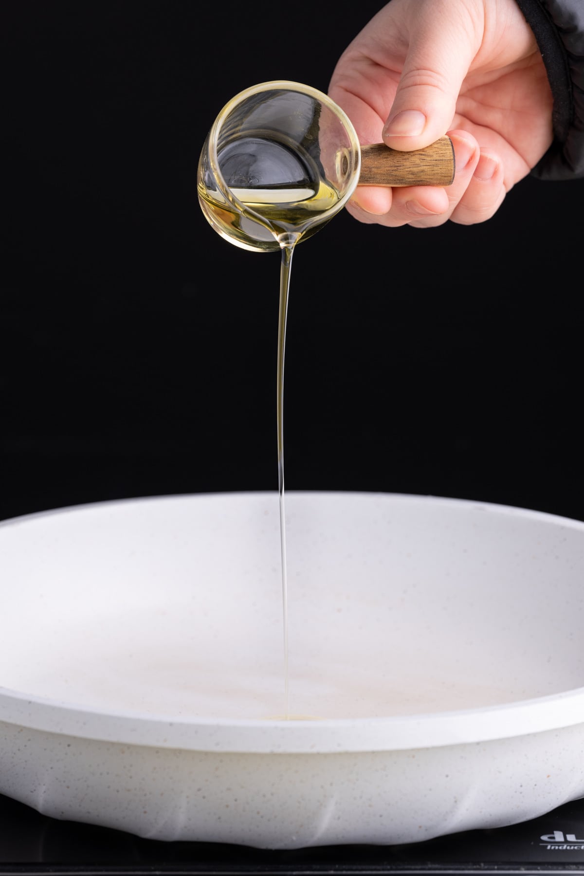 Adding olive oil to a pan to get hot before cracking eggs in it.