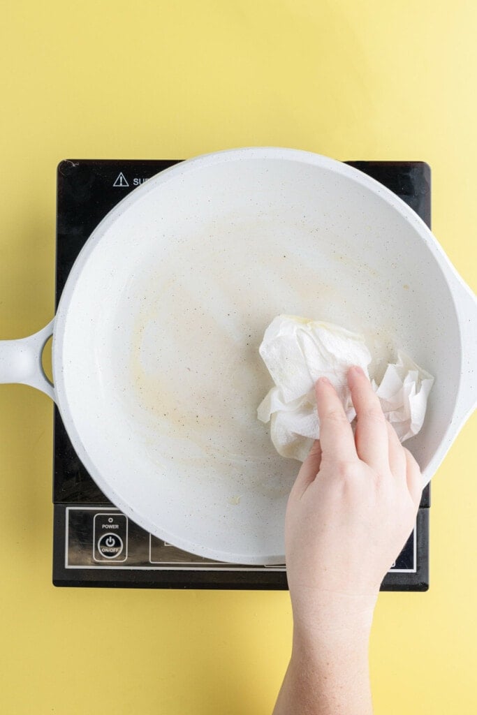Wiping pan clean with paper towel