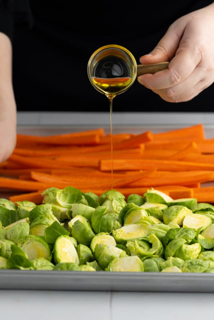 Adding olive oil to carrots and brussels sprouts to roast them