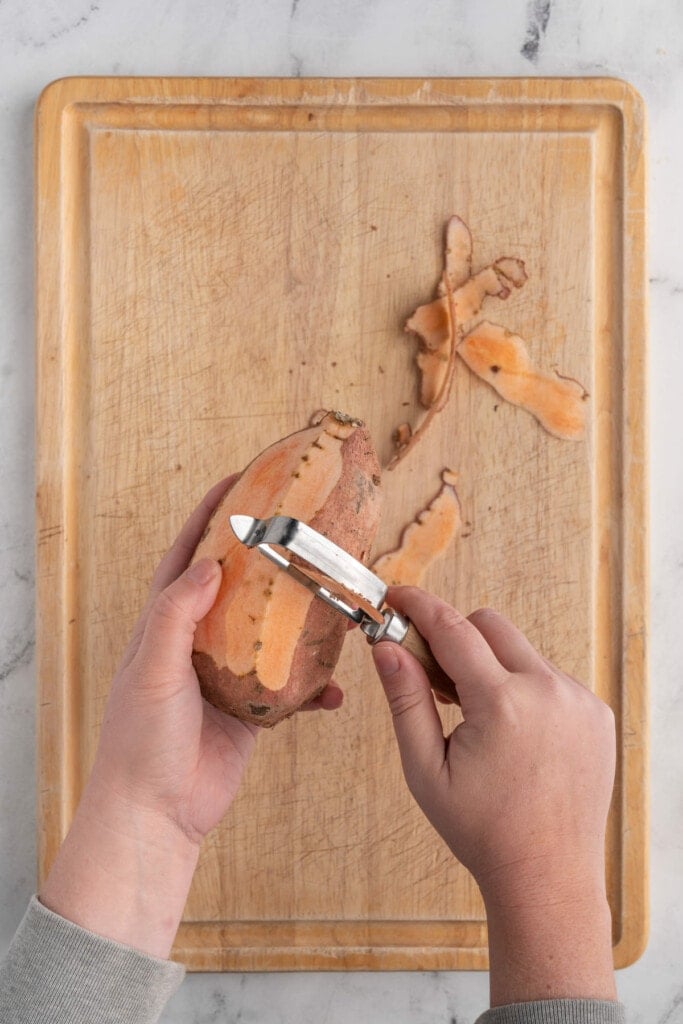 Peeling sweet potatoes with a vegetable peeler. 