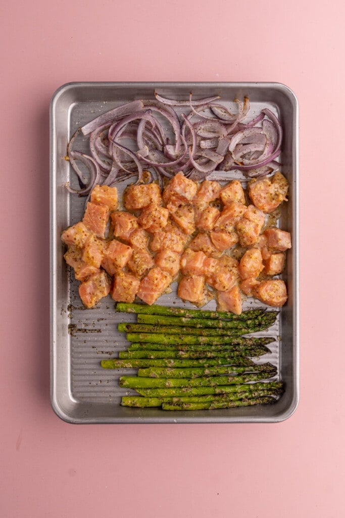 Adding cubed salmon to roast with asparagus and red onion