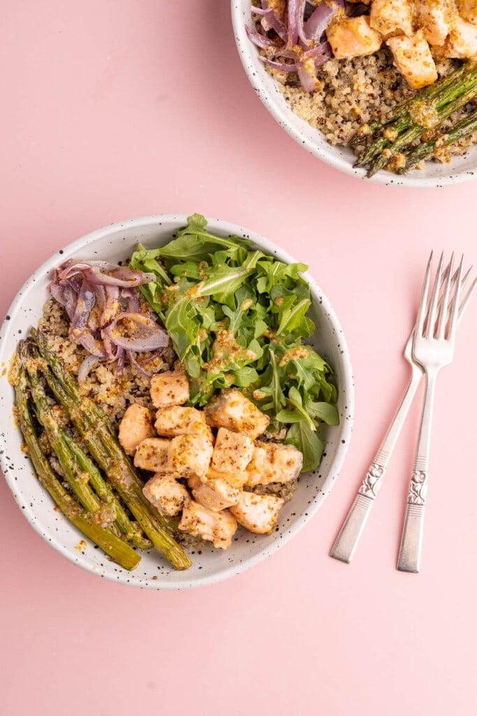 Two quinoa bowls with salmon in a honey dijon marinade