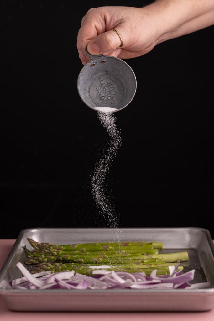 Seasoning asparagus and red onion to roast