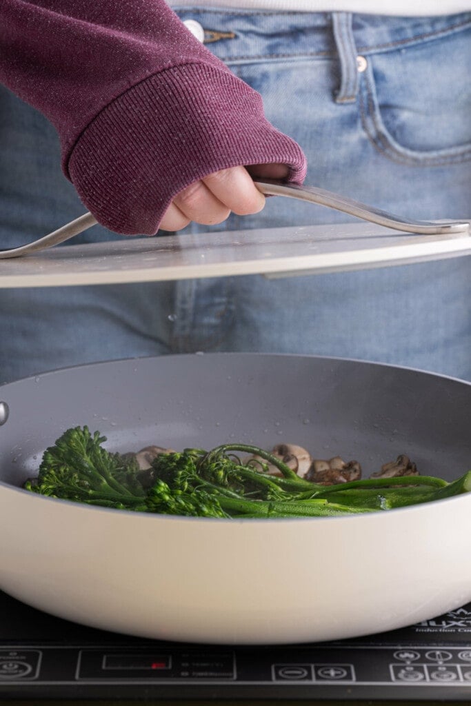 Covering pan of mushrooms and broccolini