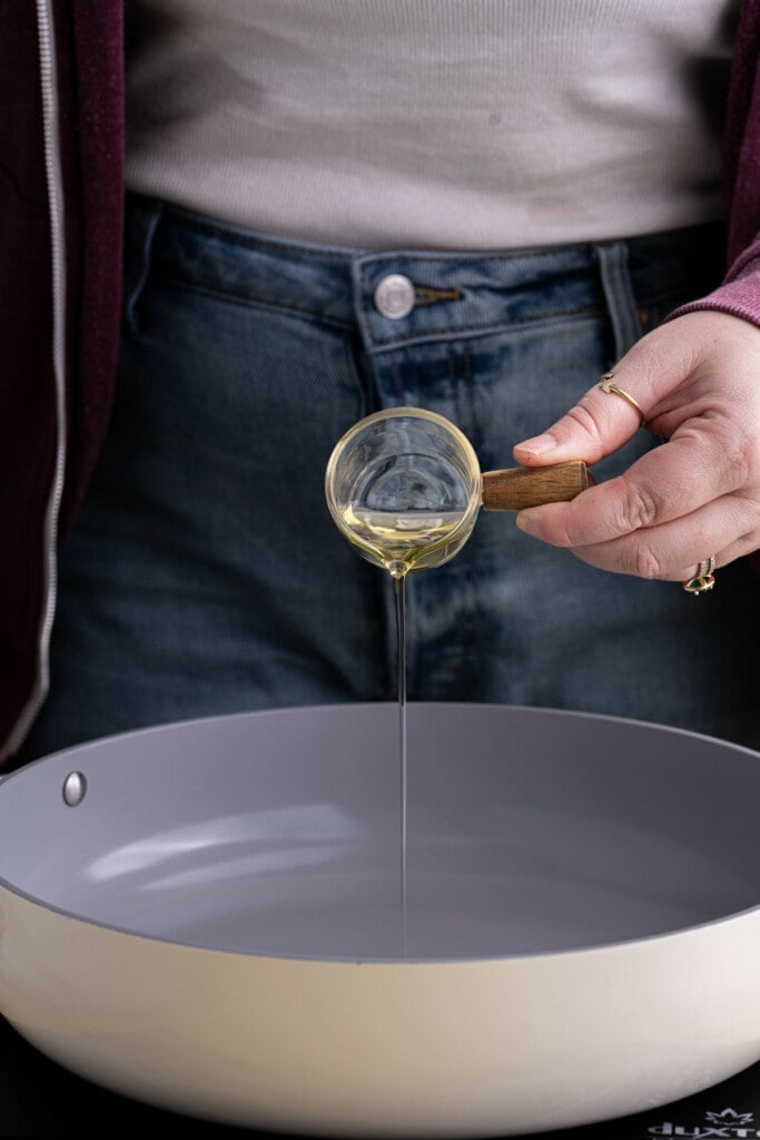 Adding olive oil to a frying pan to get hot