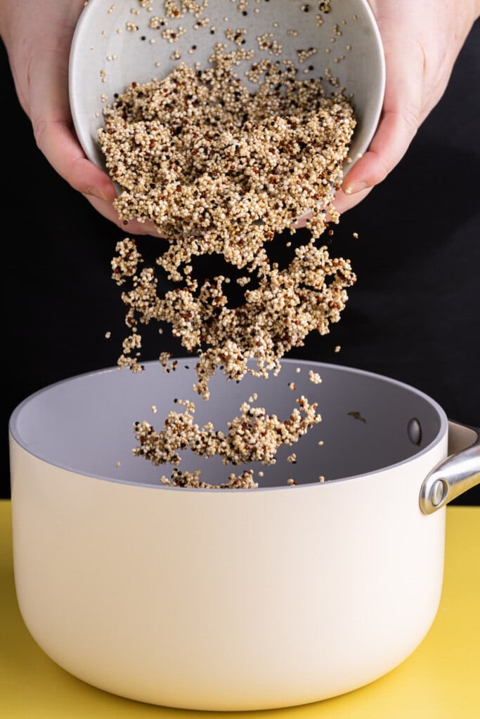 Adding rinsed quinoa to pot to cook in vegetable broth