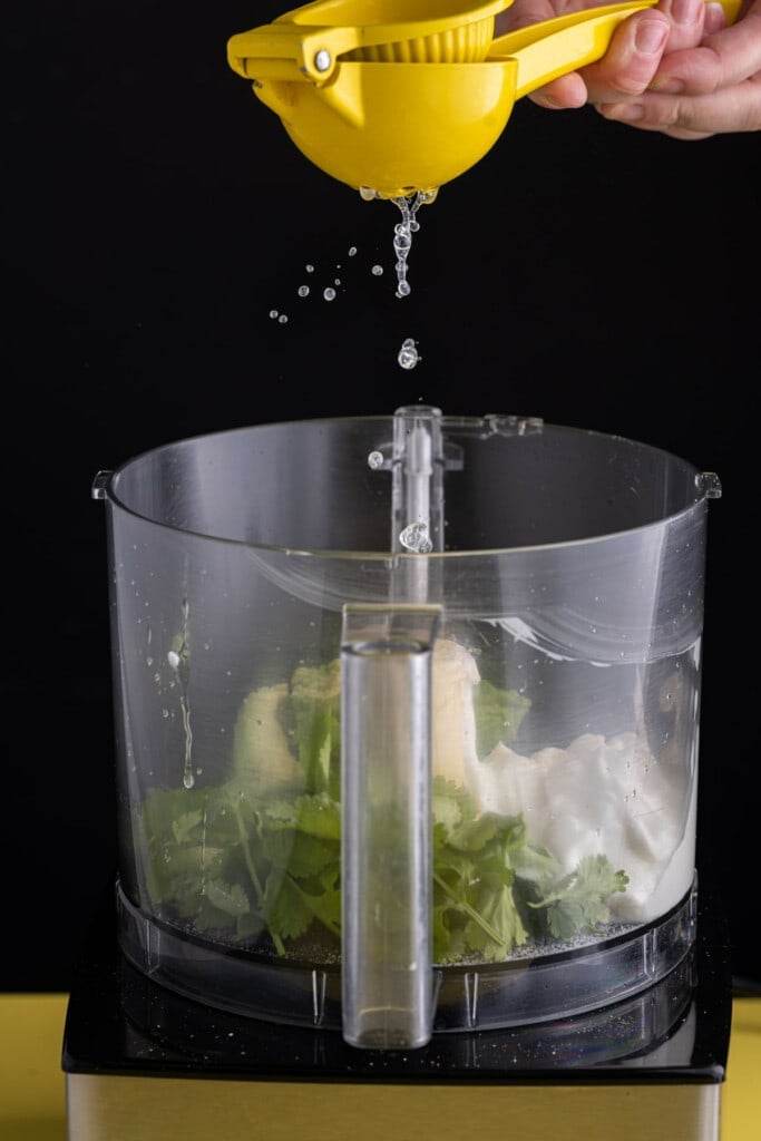 Adding fresh lime juice to food processor to make avocado crema