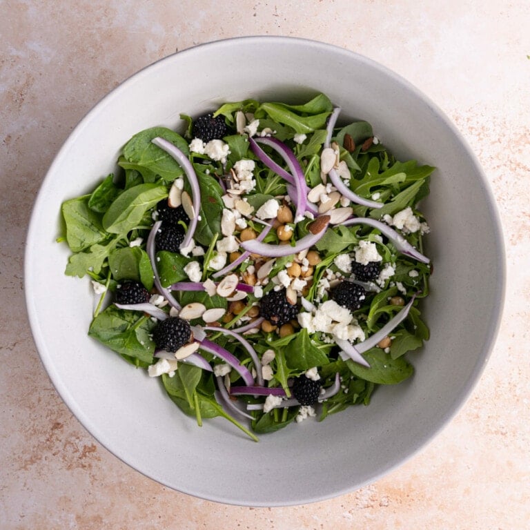 All ingredients for Spinach Arugula Salad in a large mixing bowl