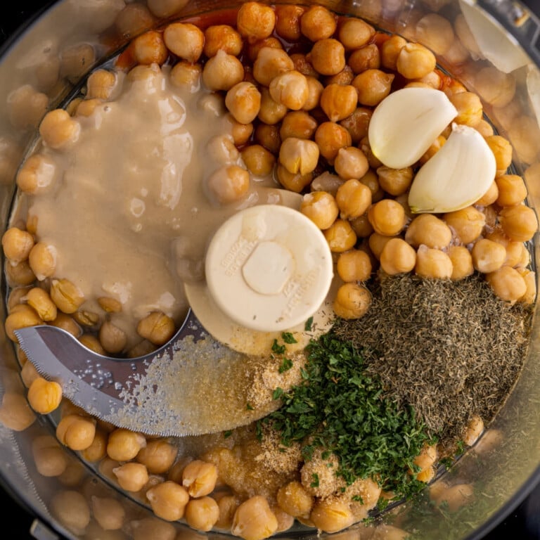 Lemon, olive oil, garlic, canned chickpeas, onion powder, hot sauce, tahini, dill, and dried parsley in a food processor