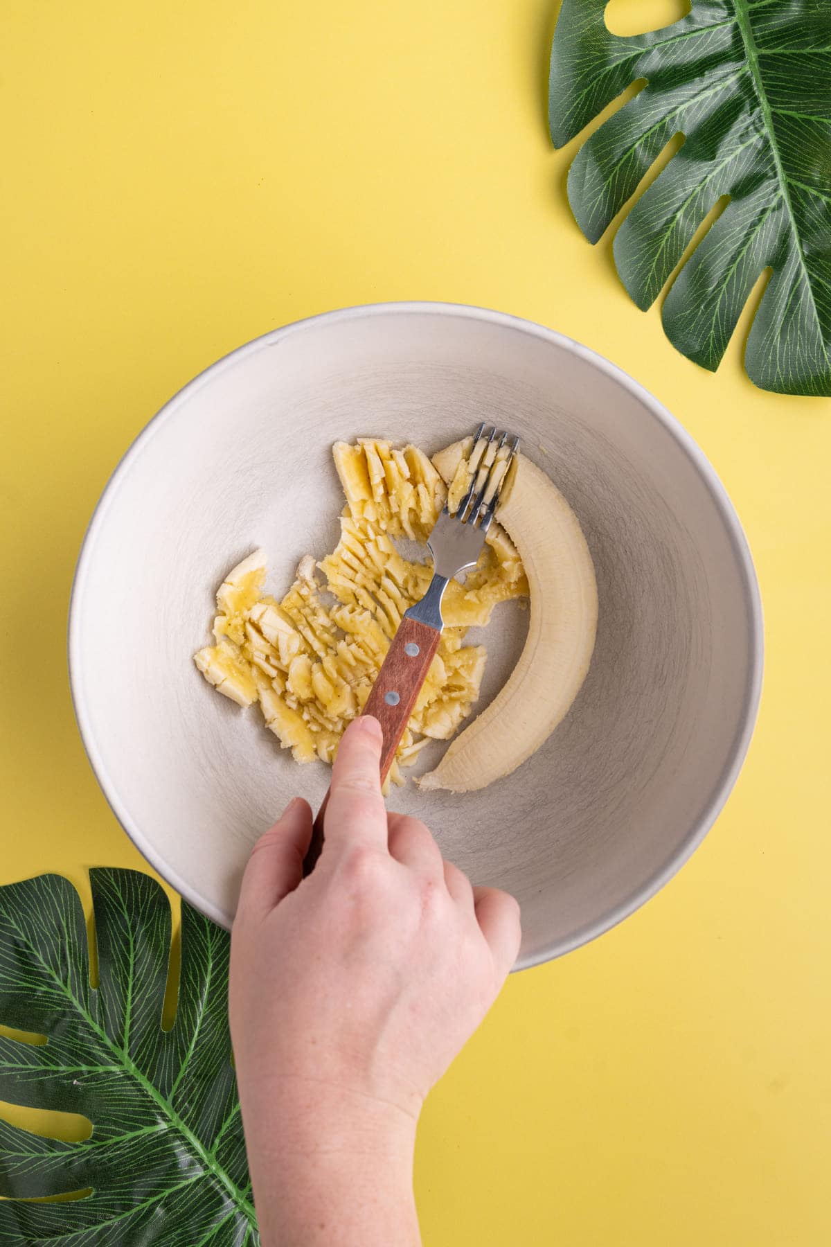 Using a fork to mash bananas for Banana Bread Cookies.