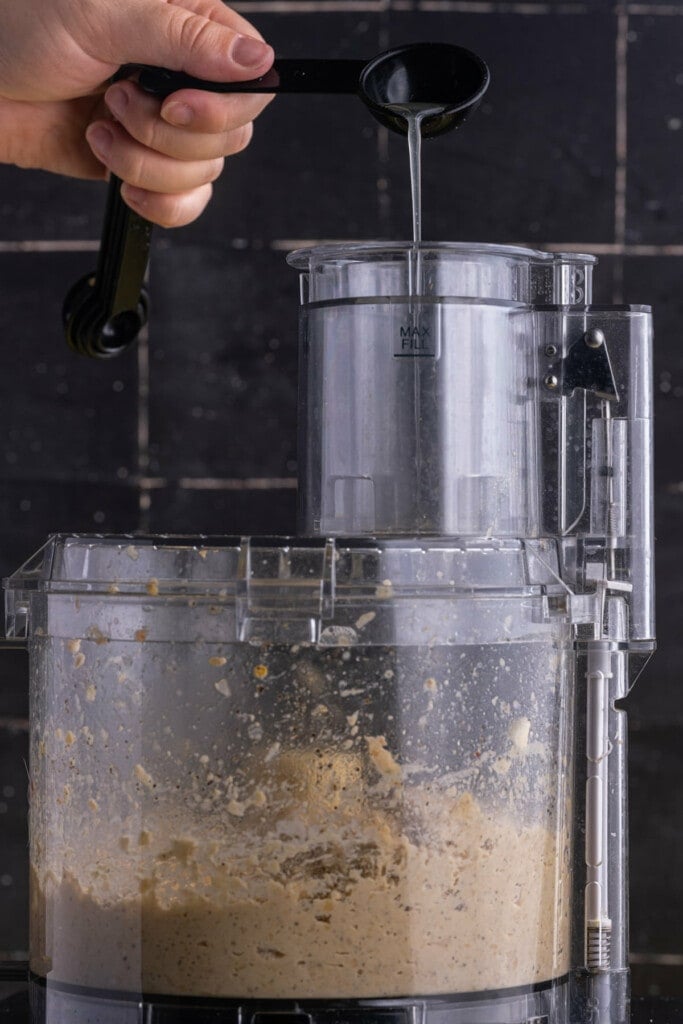 Adding aquafaba to hummus with food processor on to thin out