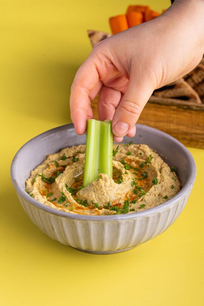 Dipping celery into Buffalo Ranch Hummus