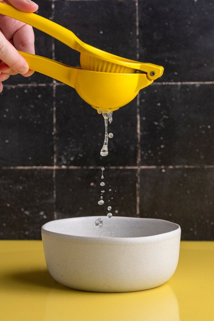 Squeezing lemon juice into a bowl with citrus squeezer