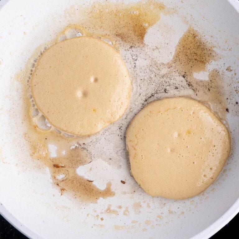 Two pancakes frying in a pan ready to flip