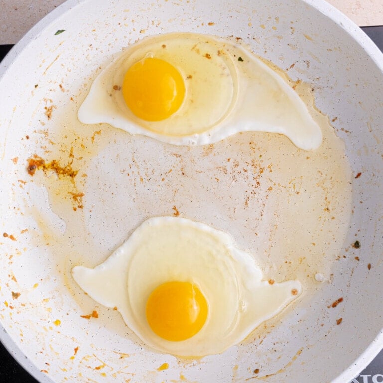 Frying two eggs in a pan for quinoa breakfast bowl