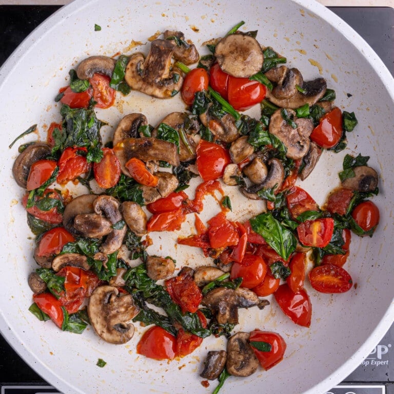 Frying up spinach mushrooms and grape tomatoes in a pan