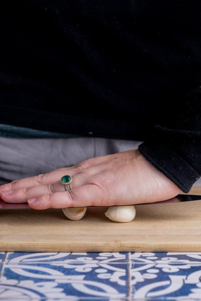 Using flat end of knife to crush garlic and make it easier to peel