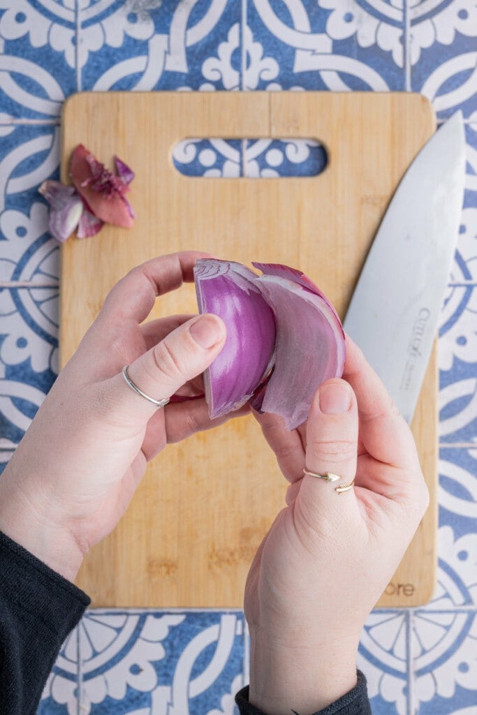 Peeling the outermost layer off of a red onion