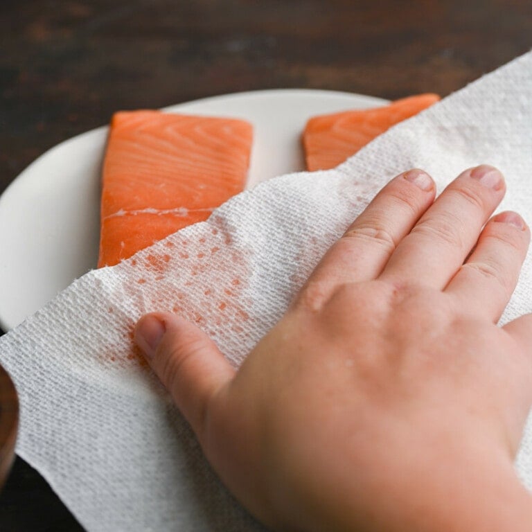Patting salmon dry with a paper towel
