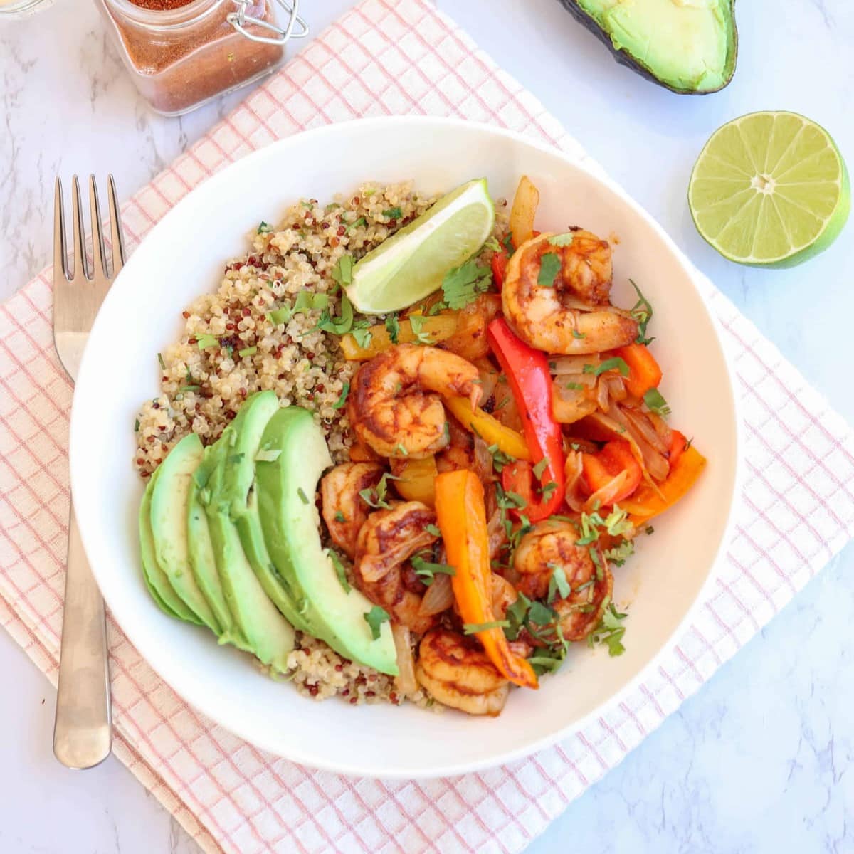 Shrimp Fajita Quinoa Bowl Featured Image on a tablecloth with a fork and half a lime