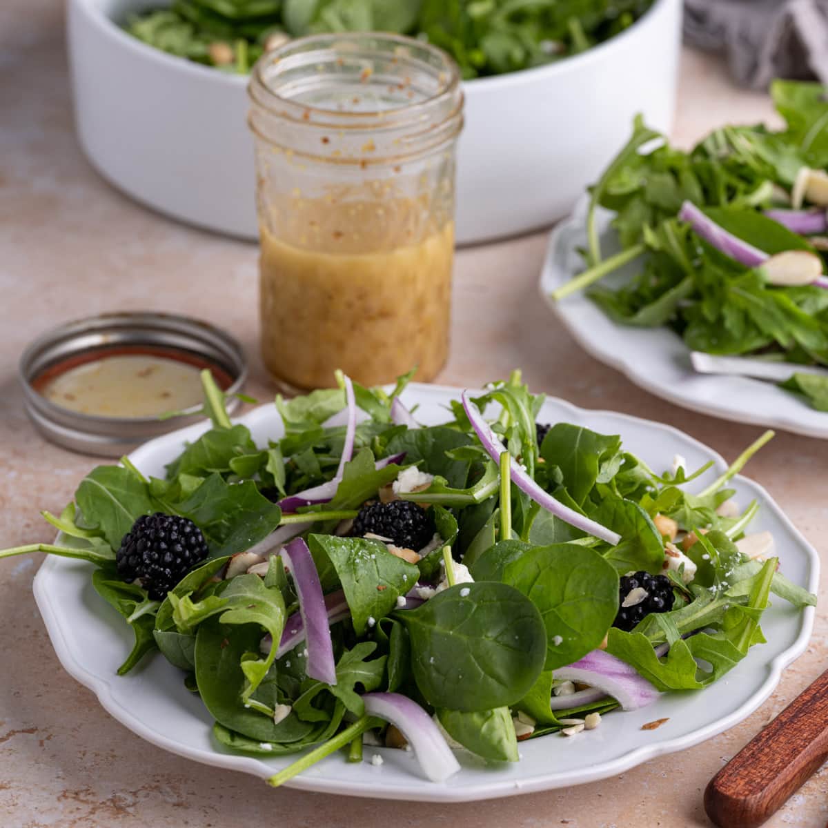 Plate of Spinach Arugula Salad with Honey Dijon Vinaigrette behind it