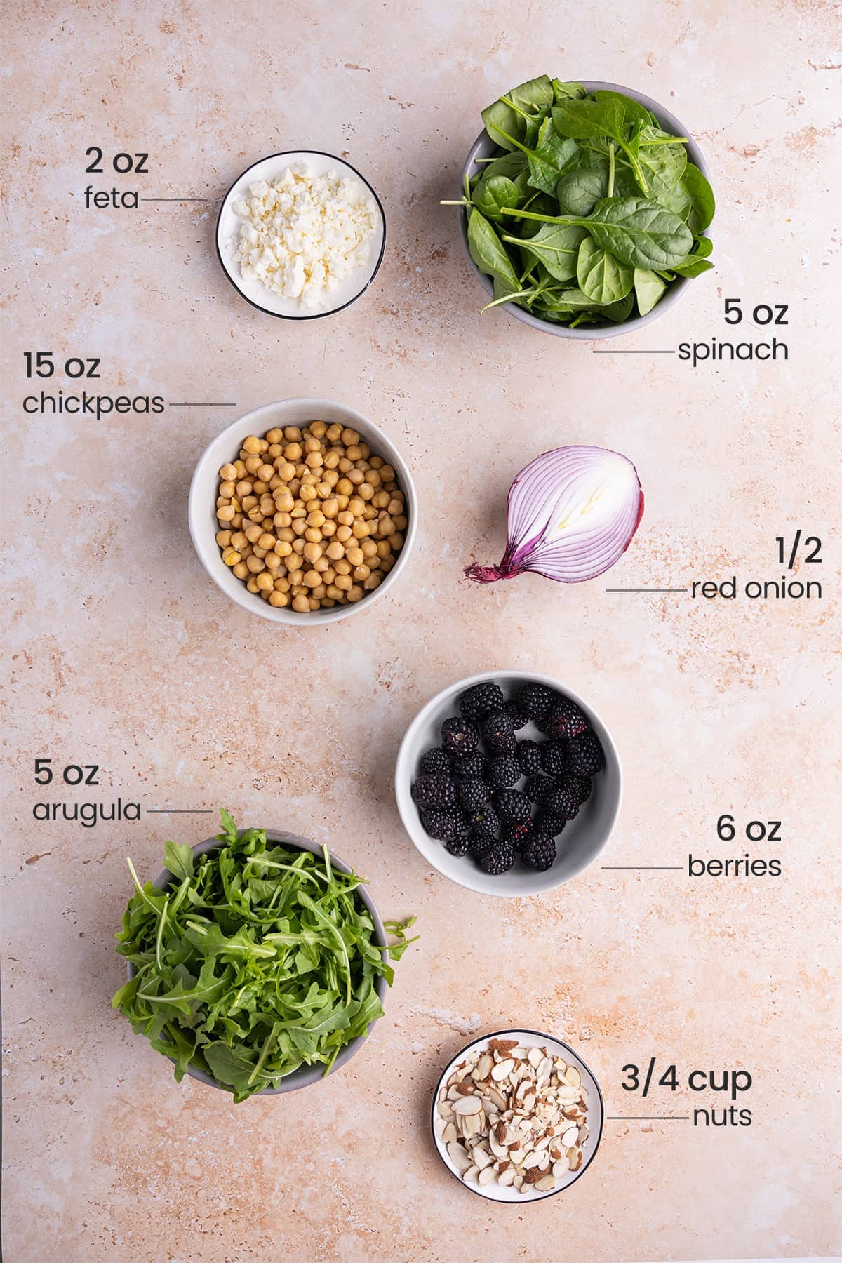 ingredients for spinach arugula salad - feta cheese, spinach, chickpeas, red onion, arugula, berries, nuts