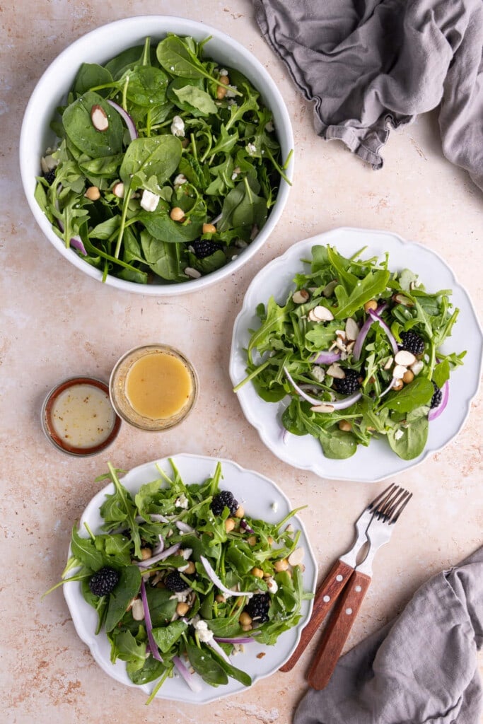 Two plates of Spinach Arugula Salad next to the serving bowl 