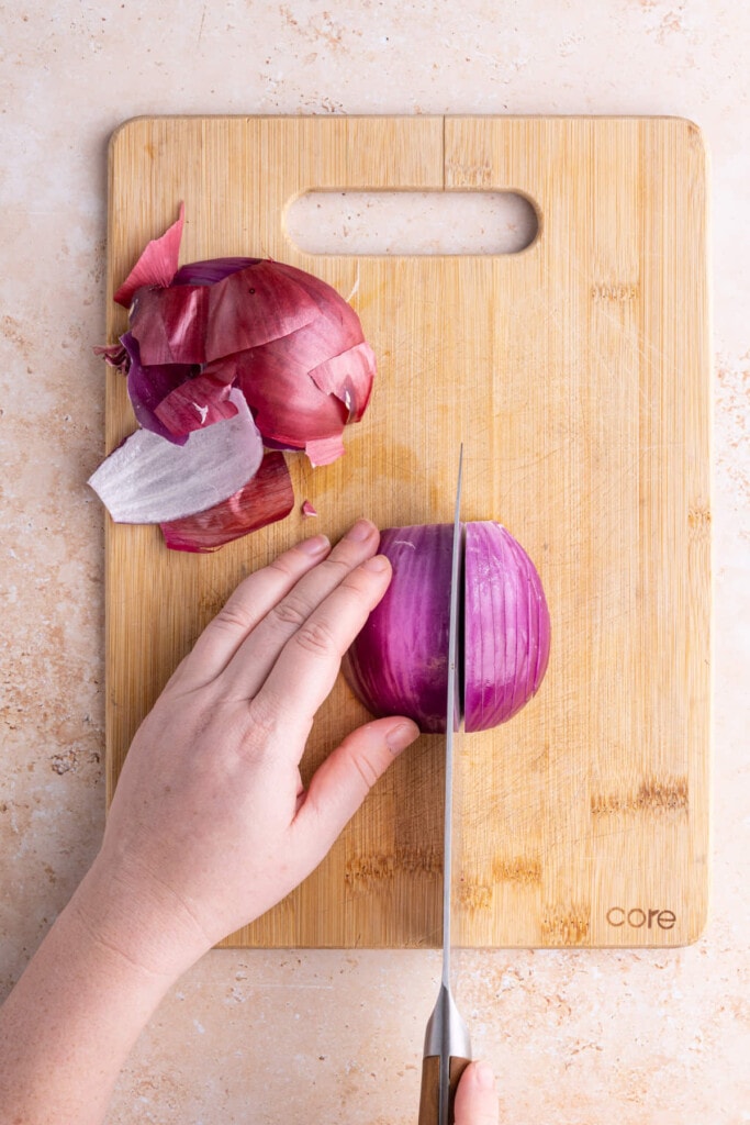 Laying onion flat to slice into thin strips