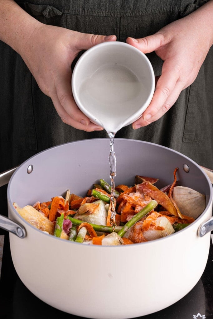 Adding enough water to the pot to cover the scraps