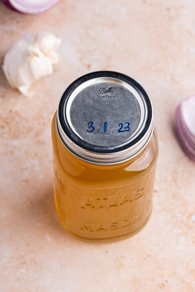 Storing veggie scrap broth in glass jar and writing date on lid