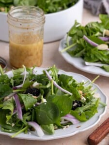 Plate of Spinach Arugula Salad with Honey Dijon Vinaigrette behind it