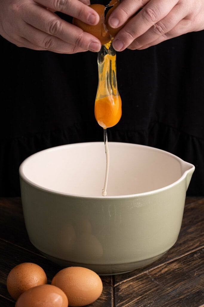 Cracking an egg in a large mixing bowl to make quiche filling