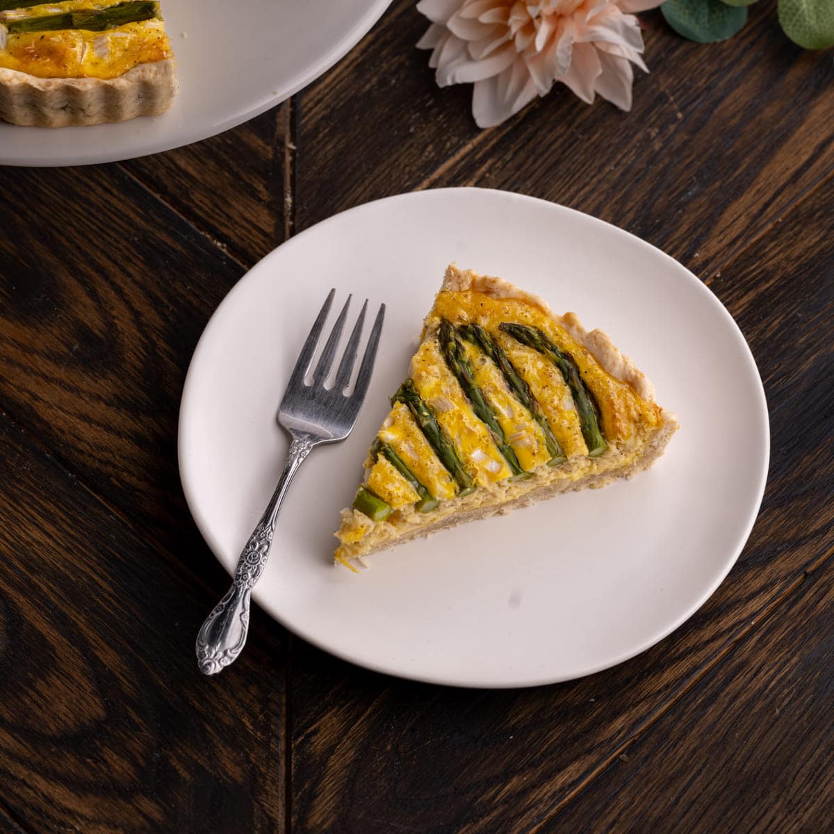 Slice of asparagus quiche on a plate with a fork