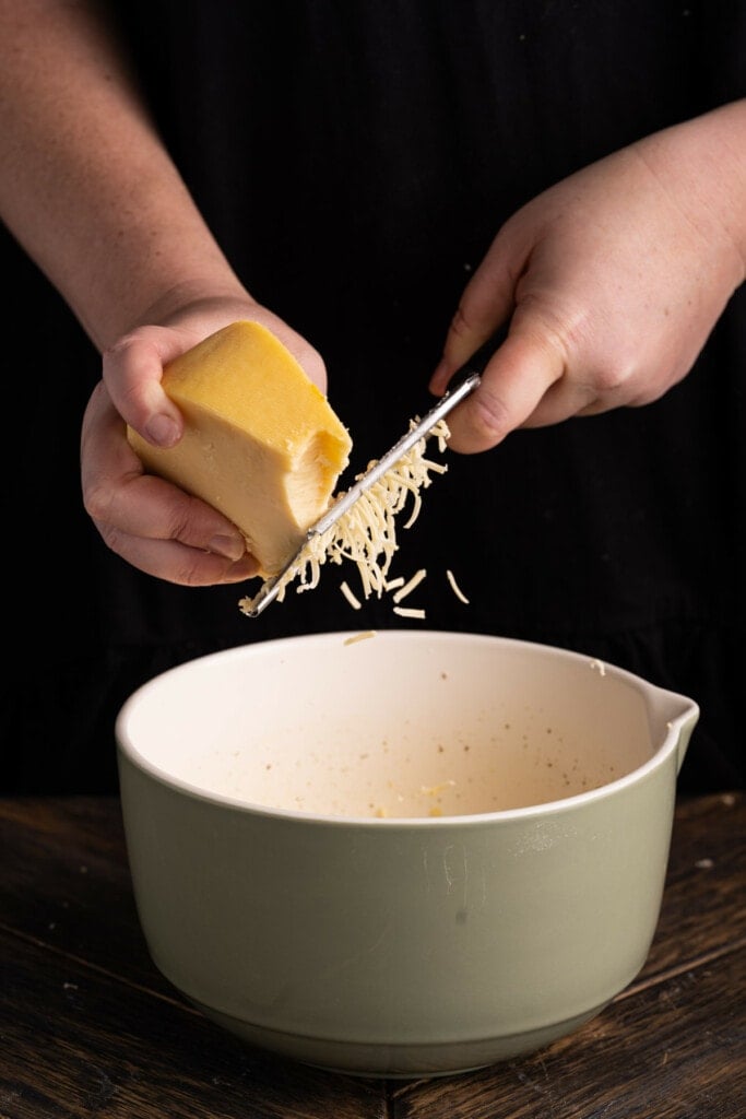 Grating gouda cheese to add to asparagus quiche