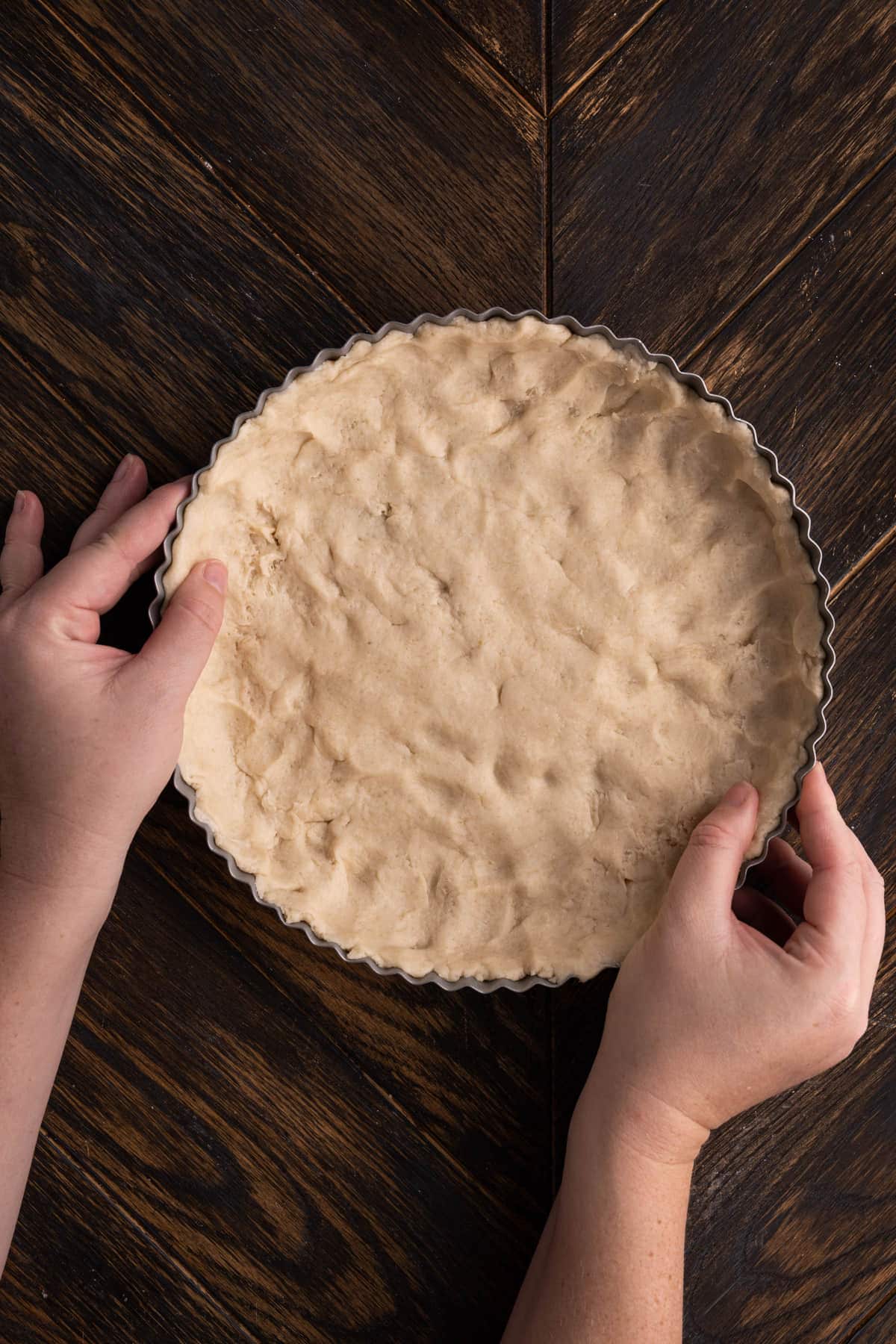 Using clean hands to push quiche crust dough into dish