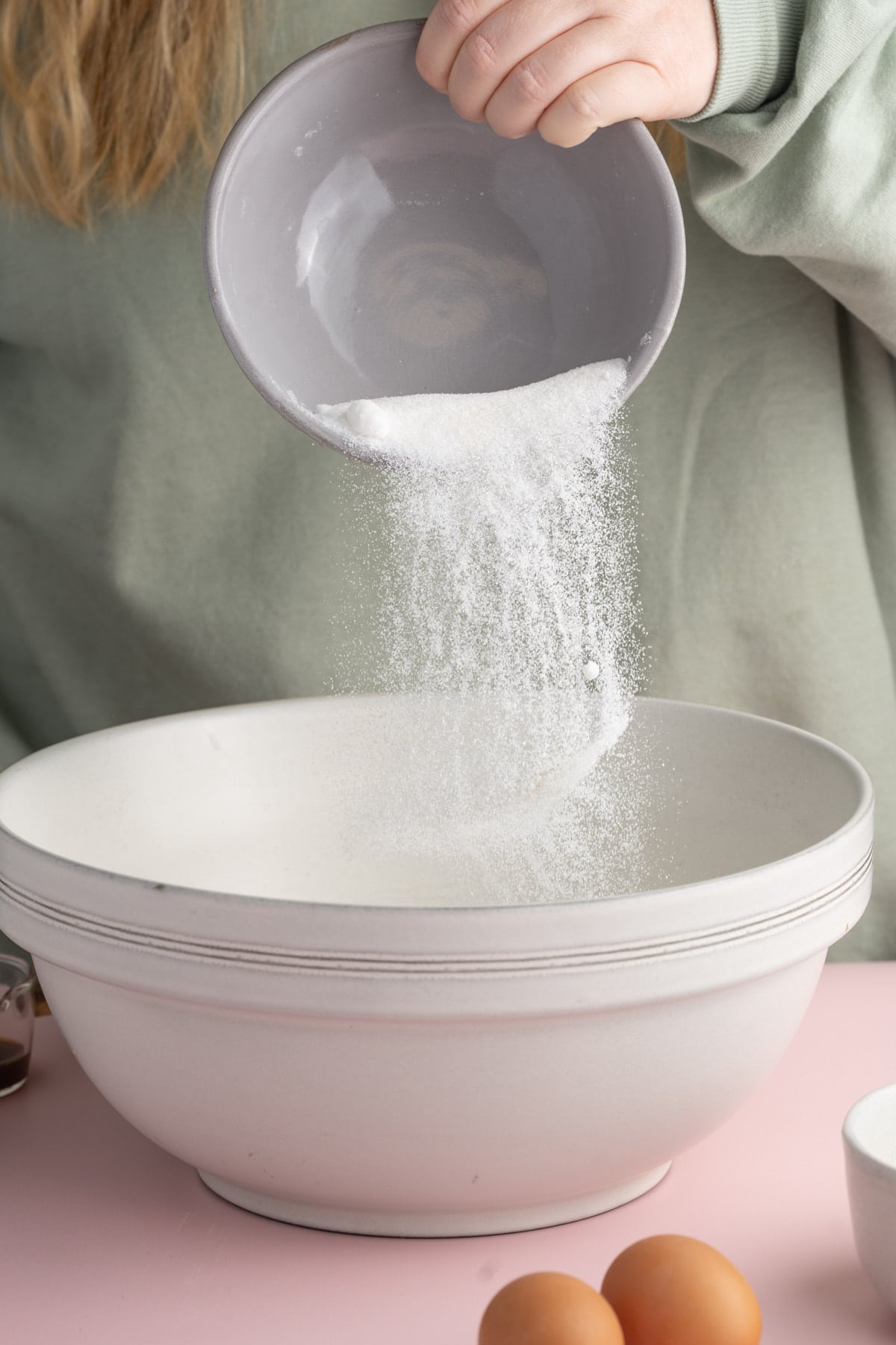 Adding granulated sugar to a bowl to make brownie batter