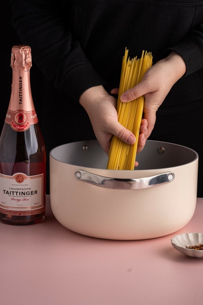 Adding linguine to pot to cook al dente.