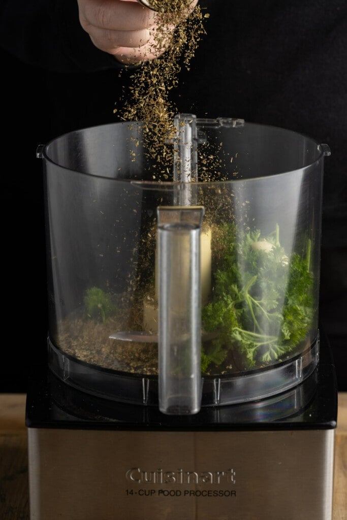 Adding dried oregano to the food processor