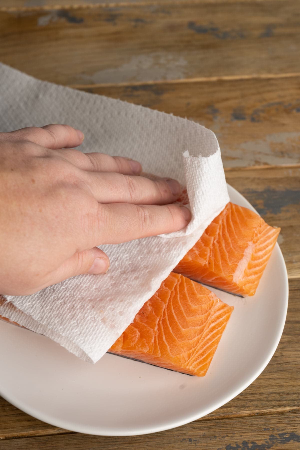 Patting salmon dry with a bamboo paper towel