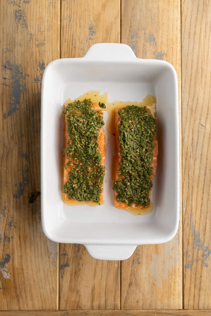Adding a generous layer of Chimichurri on top of two portions of salmon to bake