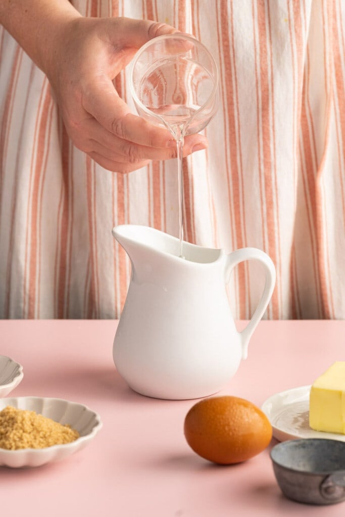 Pouring vinegar into a pitcher of milk to make acidified buttermilk