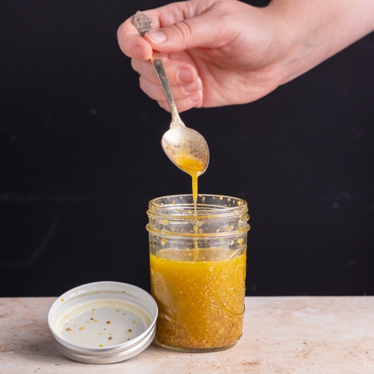 Maple Dijon Vinaigrette running off a spoon into a jar