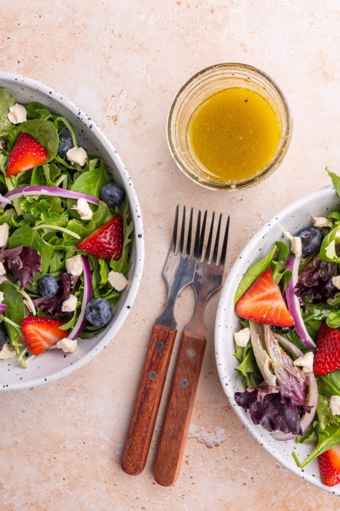 Overhead shot of two salads and a glass jar of Maple Dijon Vinaigrette