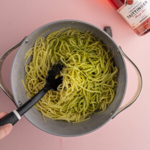 Tossing linguine in pesto and reserved pasta water